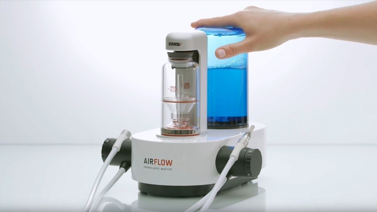 Dispositivo Airflow Prophylaxis Master con botella de líquido azul, utilizado en tratamientos dentales para profilaxis profesional